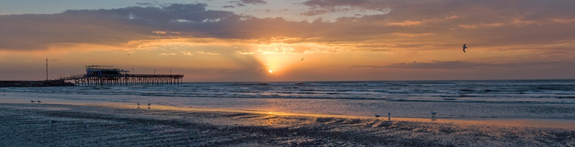 Sun setting along the beach and pier in Galveston.